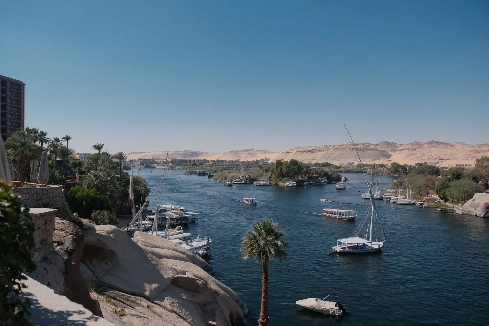 Boats, palms and rocky riverbanks in Aswan