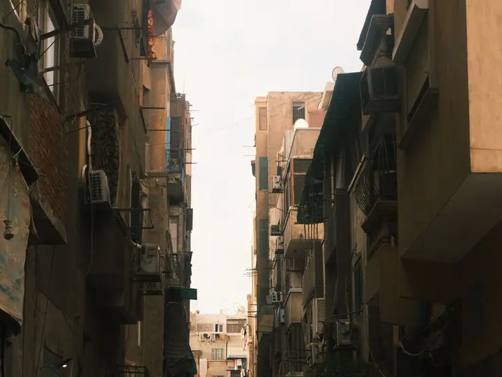 A sunlit Cairo street with warm-toned buildings and pedestrians