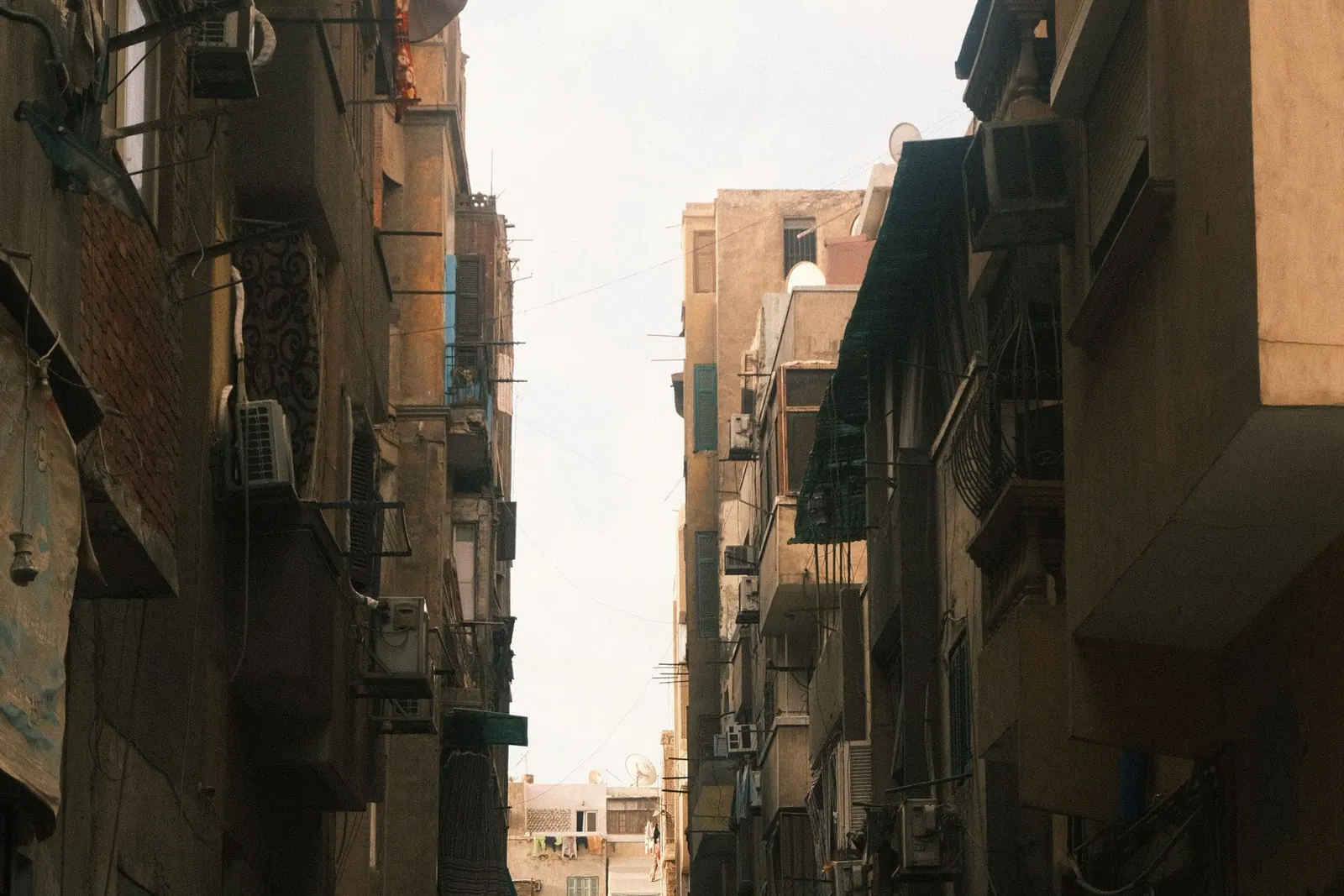 A sunlit Cairo street with warm-toned buildings and pedestrians