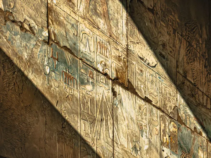 Warm sunlight casting geometric shadows on an Egyptian wall