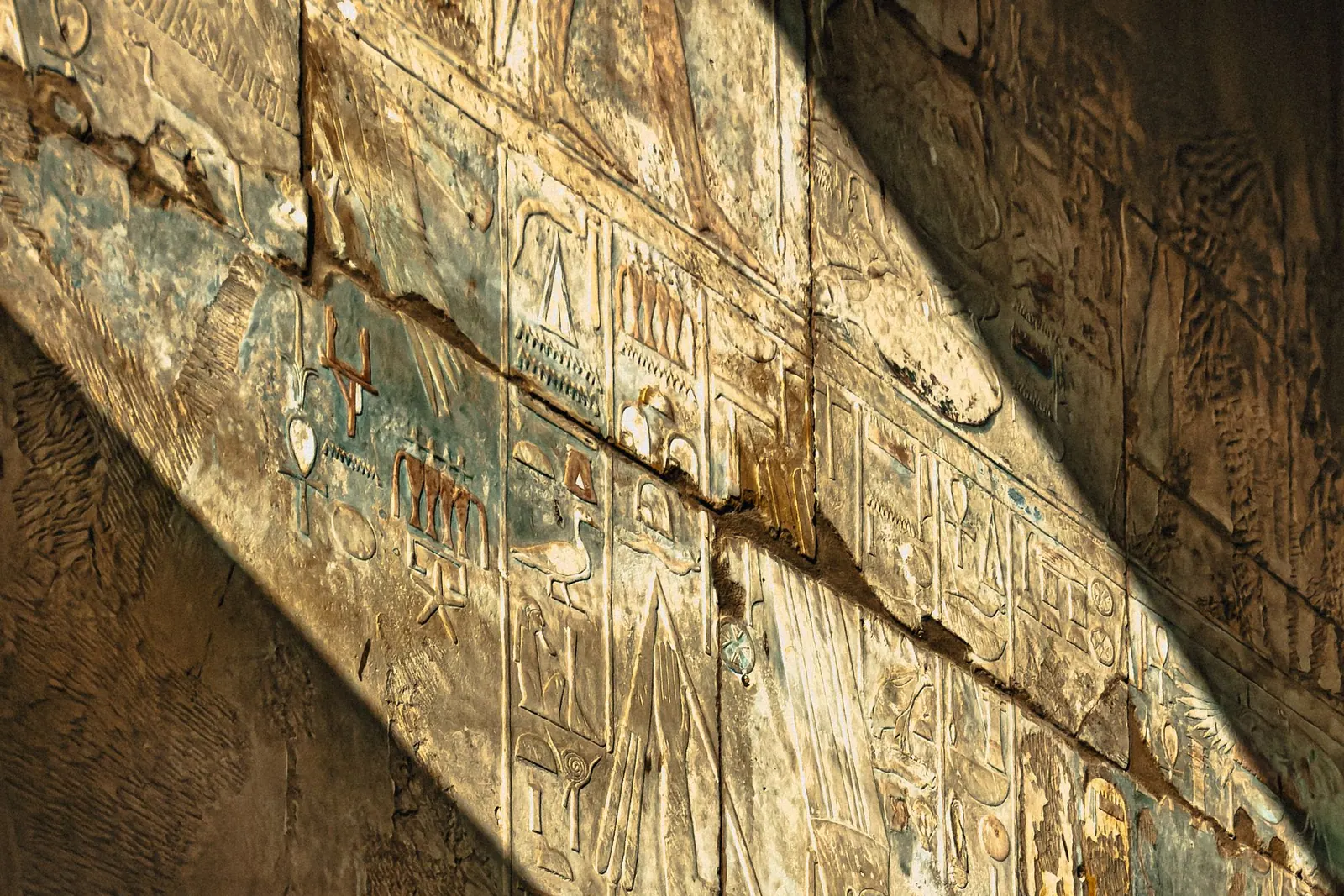 Warm sunlight casting geometric shadows on an Egyptian wall
